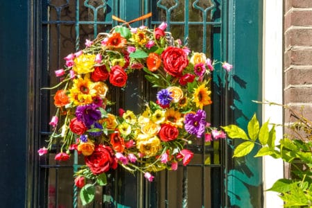 Brightly colored flower wreath hanging on a green door