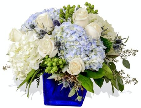 An affectionate mix of cool-toned flowers cascade over a deep sapphire blue glass cube making Dior Blue a timeless design for a loved-one or just because. Blue and white hydrangea, cream roses and, eryngium can help brighten anyone's day.