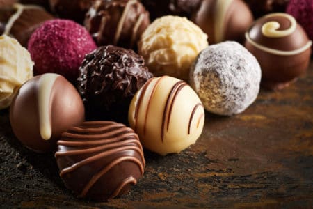 Luxury handmade decorative chocolate bonbon in a display of assorted pralines with selective focus in close up view on rustic wood