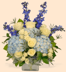 a delightful arrangement full of white spray roses and premium roses, blue hydrangeas, blue eryngium, blue delphinium, and more!