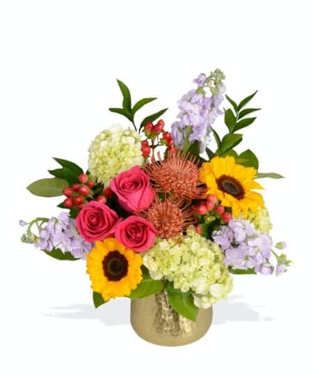 Send them sunny spring flowers with bright & vibrant "Here Comes the Sun" arrangement, full of sunflowers, roses, pincushion protea and more in a gold Hux Pot from Accent Decor!